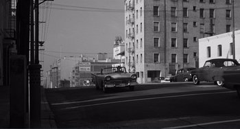 Movie still from “My Gun Is Quick” (1957), directed by Victor Saville – An old black and white photo of a car driving down a street; Extreme Wide shot, High angle