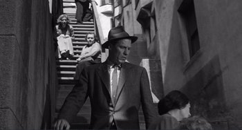 Movie still from “My Gun Is Quick” (1957), directed by Victor Saville – A black and white photo of a man in a suit and hat; Medium shot, Low angle