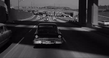 Movie still from “My Gun Is Quick” (1957), directed by Victor Saville – A black and white photo of a car on a freeway; Extreme Wide shot, High angle