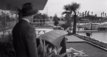 Movie still from “My Gun Is Quick” (1957), directed by Victor Saville – A man and a woman sitting on a bench in a park; Wide shot, Over the shoulder angle