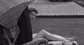 Movie still from “My Gun Is Quick” (1957), directed by Victor Saville – A black and white photo of a woman sitting under an awning; Medium shot, High angle