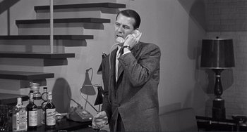 Movie still from “My Gun Is Quick” (1957), directed by Victor Saville – A black and white photo of a man talking on a phone; Medium shot, Low angle