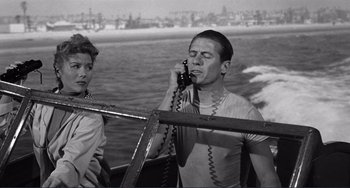 Movie still from “My Gun Is Quick” (1957), directed by Victor Saville – A man talking on a phone next to another man; Medium shot, High angle