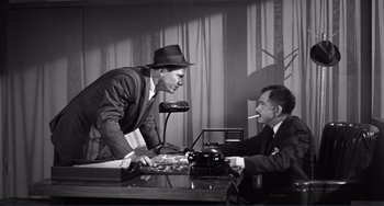 Movie still from “My Gun Is Quick” (1957), directed by Victor Saville – Two men sitting at a table with a phone; Medium shot, Over the shoulder angle