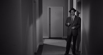 Movie still from “My Gun Is Quick” (1957), directed by Victor Saville – A black and white photo of a man in a suit and hat; Medium shot, Over the shoulder angle