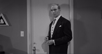 Movie still from “My Gun Is Quick” (1957), directed by Victor Saville – Black and white photograph of a man in a suit; Medium shot, Low angle