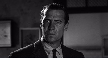 Movie still from “My Gun Is Quick” (1957), directed by Victor Saville – Black and white photograph of a man in a suit and tie; Close Up shot, Low angle