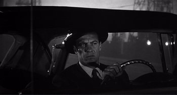 Movie still from “My Gun Is Quick” (1957), directed by Victor Saville – A black and white photo of a man driving a car; Close Up shot, Low angle