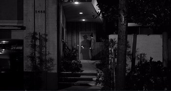 Movie still from “My Gun Is Quick” (1957), directed by Victor Saville – A man is standing in the doorway of a house at night; Wide shot, Low angle