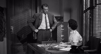 Movie still from “My Gun Is Quick” (1957), directed by Victor Saville – A man and a woman are sitting at a desk; Medium shot, Over the shoulder angle