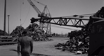 Movie still from “My Gun Is Quick” (1957), directed by Victor Saville – A man standing in front of a pile of debris; Wide shot, Low angle