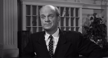 Movie still from “My Gun Is Quick” (1957), directed by Victor Saville – An older man in a black suit and a polka dot tie; Close Up shot, Low angle