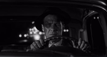 Movie still from “My Gun Is Quick” (1957), directed by Victor Saville – A black and white photo of a man driving a car; Close Up shot, Over the shoulder angle