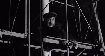 Movie still from “My Gun Is Quick” (1957), directed by Victor Saville – A black and white photo of a man on a scaffold; Medium shot, Low angle