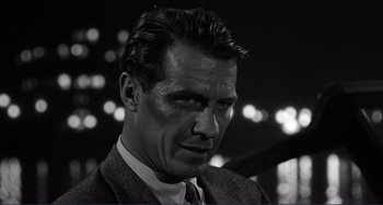 Movie still from “My Gun Is Quick” (1957), directed by Victor Saville – Black and white photograph of a man in a suit and tie; Close Up shot, Low angle