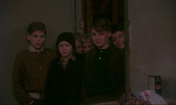 Movie still from “My Life as a Dog” (1985), directed by Lasse Hallström – A group of young people standing next to each other in a room; Medium shot, High angle