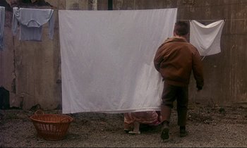 Movie still from “My Life as a Dog” (1985), directed by Lasse Hallström – A man and a woman standing in front of a white sheet; Wide shot, Over the shoulder angle