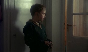 Movie still from “My Life as a Dog” (1985), directed by Lasse Hallström – A young boy standing in front of a door; Medium shot, Over the shoulder angle