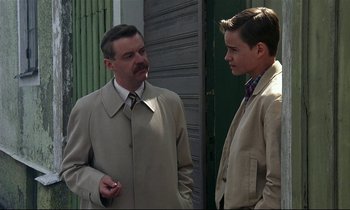 Movie still from “My Life as a Dog” (1985), directed by Lasse Hallström – A man and a young man standing next to each other; Medium shot, Over the shoulder angle