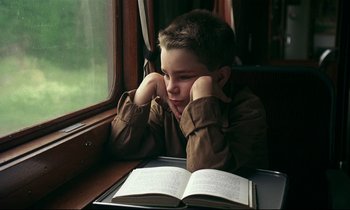 Movie still from “My Life as a Dog” (1985), directed by Lasse Hallström – A young boy sitting in front of an open book; Close Up shot, High angle