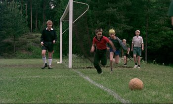 Movie still from “My Life as a Dog” (1985), directed by Lasse Hallström – A group of young people playing a game of soccer on a field; Wide shot, High angle