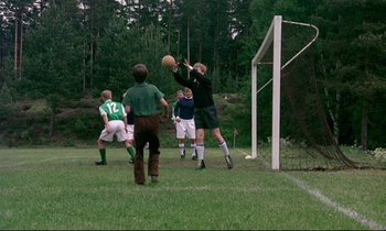 Movie still from “My Life as a Dog” (1985), directed by Lasse Hallström – A group of young men playing a game of soccer on a soccer field; Wide shot, Low angle