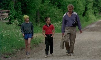 Movie still from “My Life as a Dog” (1985), directed by Lasse Hallström – A man and two young boys walking down a dirt road; Wide shot, Low angle