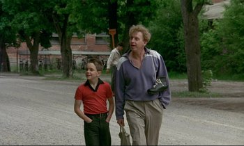 Movie still from “My Life as a Dog” (1985), directed by Lasse Hallström – A man and a boy walking down a street; Medium shot, Low angle
