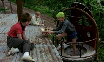 Movie still from “My Life as a Dog” (1985), directed by Lasse Hallström – A group of young people sitting on a platform; Wide shot, High angle