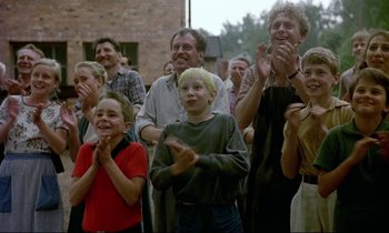 Movie still from “My Life as a Dog” (1985), directed by Lasse Hallström – A group of people standing next to each other clapping; Medium shot, Low angle