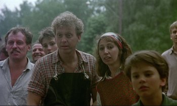 Movie still from “My Life as a Dog” (1985), directed by Lasse Hallström – A group of people standing next to each other in the woods; Medium shot, Over the shoulder angle
