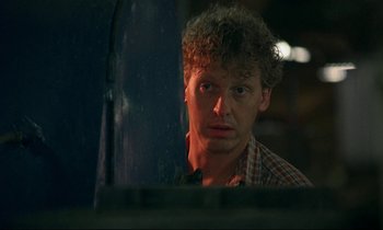 Movie still from “My Life as a Dog” (1985), directed by Lasse Hallström – A man with curly red hair and a checkered shirt looking at the camera; Close Up shot, Over the shoulder angle