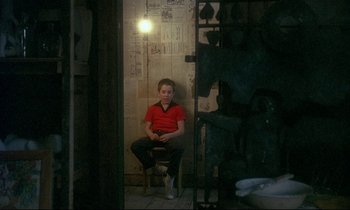 Movie still from “My Life as a Dog” (1985), directed by Lasse Hallström – A boy sitting in a chair in front of a window; Wide shot, High angle