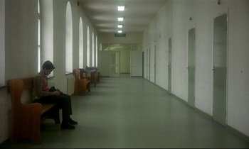 Movie still from “My Life as a Dog” (1985), directed by Lasse Hallström – People sitting on benches in an empty hospital hallway; Wide shot, High angle