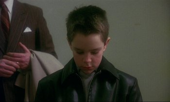 Movie still from “My Life as a Dog” (1985), directed by Lasse Hallström – A young boy wearing a black leather jacket looking down; Close Up shot, Over the shoulder angle
