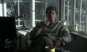 Movie still from “My Life as a Dog” (1985), directed by Lasse Hallström – A man sitting in a chair in a living room; Medium shot, Low angle