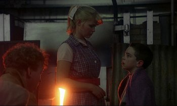 Movie still from “My Life as a Dog” (1985), directed by Lasse Hallström – A woman standing next to a boy with a light in his hand; Medium shot, Over the shoulder angle