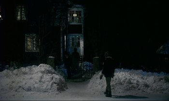 Movie still from “My Life as a Dog” (1985), directed by Lasse Hallström – A person is walking in the snow near a house; Wide shot, Low angle