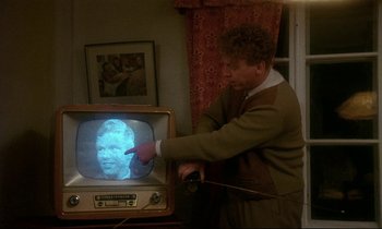 Movie still from “My Life as a Dog” (1985), directed by Lasse Hallström – A man pointing to a picture on a television screen; Close Up shot, Over the shoulder angle