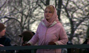 Movie still from “My Life as a Dog” (1985), directed by Lasse Hallström – A woman in a pink jacket standing next to a fence; Medium shot, Low angle