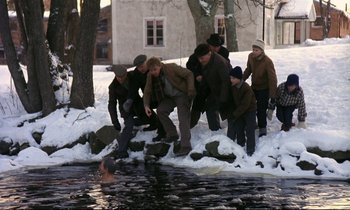 Movie still from “My Life as a Dog” (1985), directed by Lasse Hallström – A group of people standing around a body of water in the snow; Wide shot, High angle
