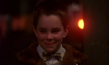 Movie still from “My Life as a Dog” (1985), directed by Lasse Hallström – A young boy wearing a bow tie and a brown jacket; Close Up shot, Over the shoulder angle