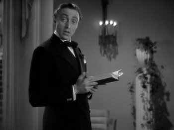 Movie still from “My Man Godfrey” (1936), directed by Gregory La Cava – A man in a suit and tie holding a book in his hands; Medium shot, Low angle
