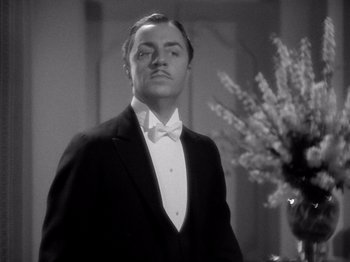 Movie still from “My Man Godfrey” (1936), directed by Gregory La Cava – A man in a tuxedo standing in front of a vase of flowers; Close Up shot, Low angle