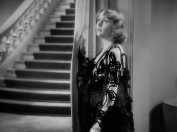 Movie still from “My Man Godfrey” (1936), directed by Gregory La Cava – A black and white photo of a woman standing in front of a staircase; Medium shot, High angle