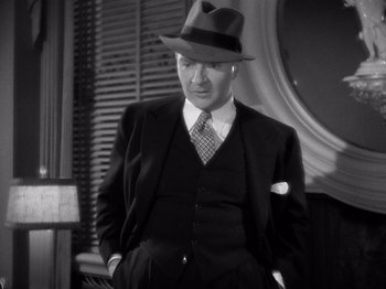 Movie still from “My Man Godfrey” (1936), directed by Gregory La Cava – A man in a suit and hat standing in front of a mirror; Medium shot, High angle