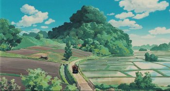 Movie still from “My Neighbor Totoro” (1988), directed by Hayao Miyazaki – A train traveling down a track near a lush green field; Extreme Wide shot, High angle