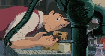 Movie still from “My Neighbor Totoro” (1988), directed by Hayao Miyazaki – An animated man holding a cell phone up to his face; Close Up shot, Low angle