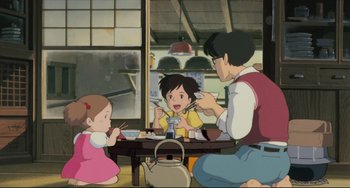 Movie still from “My Neighbor Totoro” (1988), directed by Hayao Miyazaki – A group of people sitting at a table eating food; Wide shot, High angle