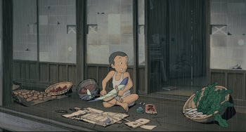 Movie still from “My Neighbor Totoro” (1988), directed by Hayao Miyazaki – An animation of a boy sitting on the floor in the rain; Wide shot, High angle
